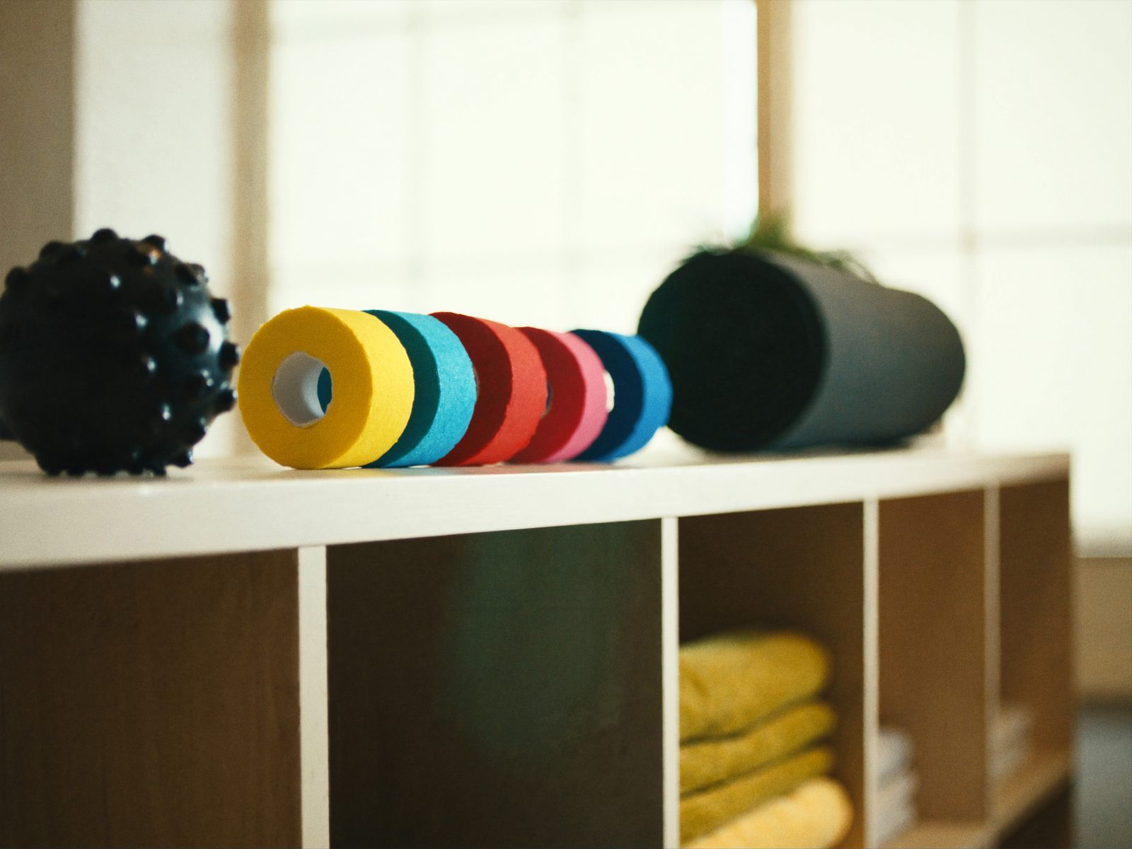 Rolls of kinesiology tape and massage tools on a shelf
