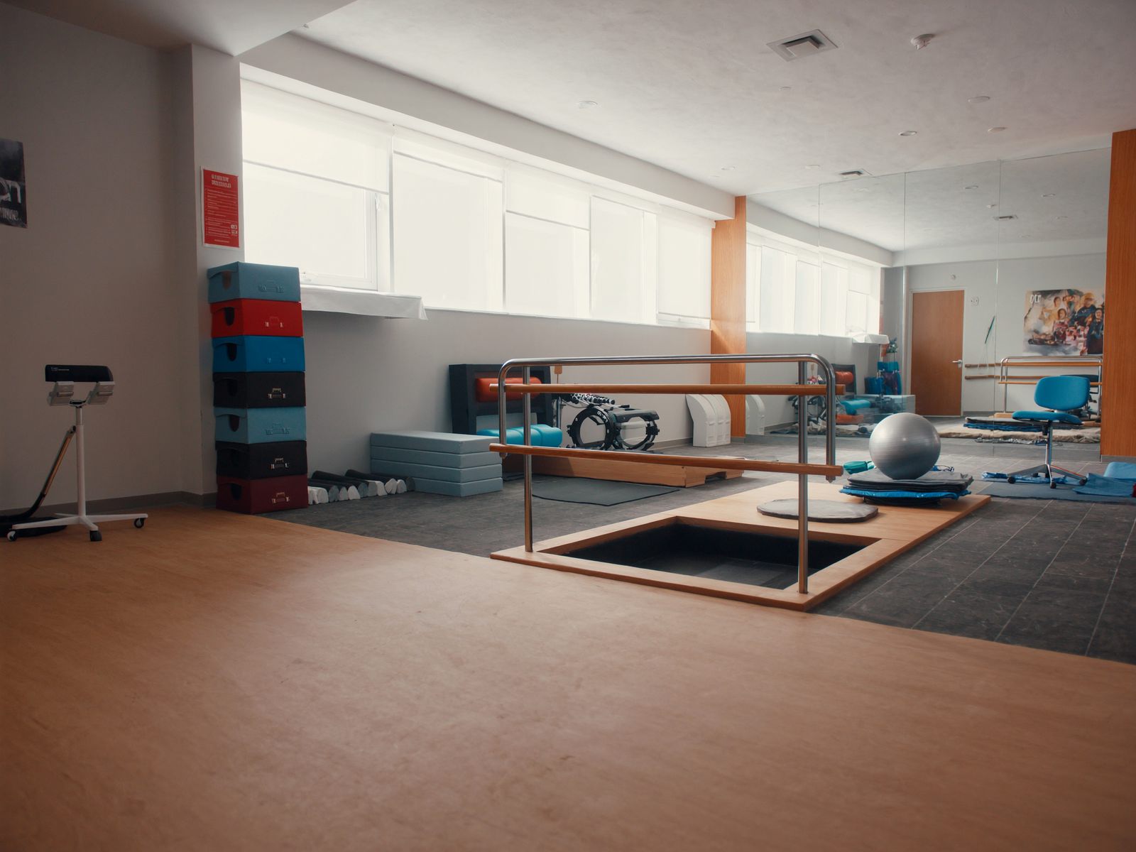 A rehab gym corner with parallel bars and balance boards