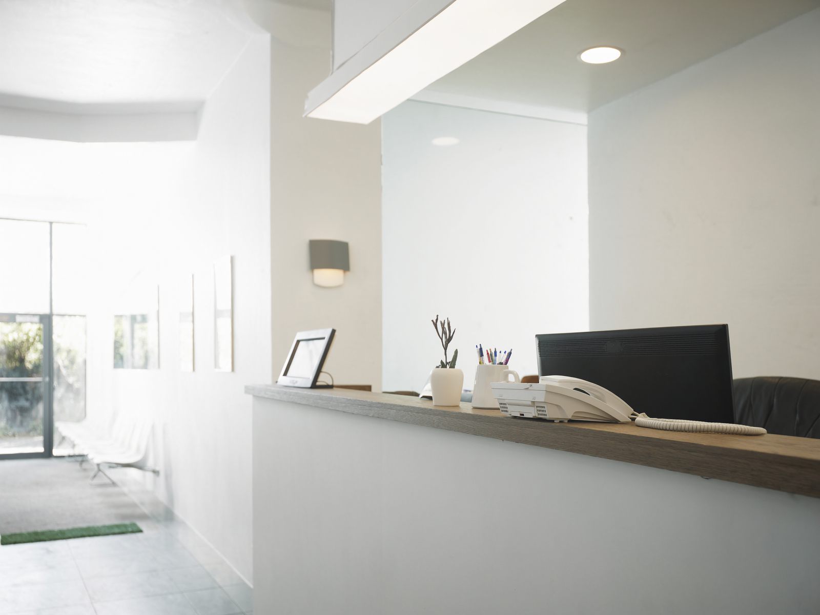 A bright dental front desk with a phone and a small plant