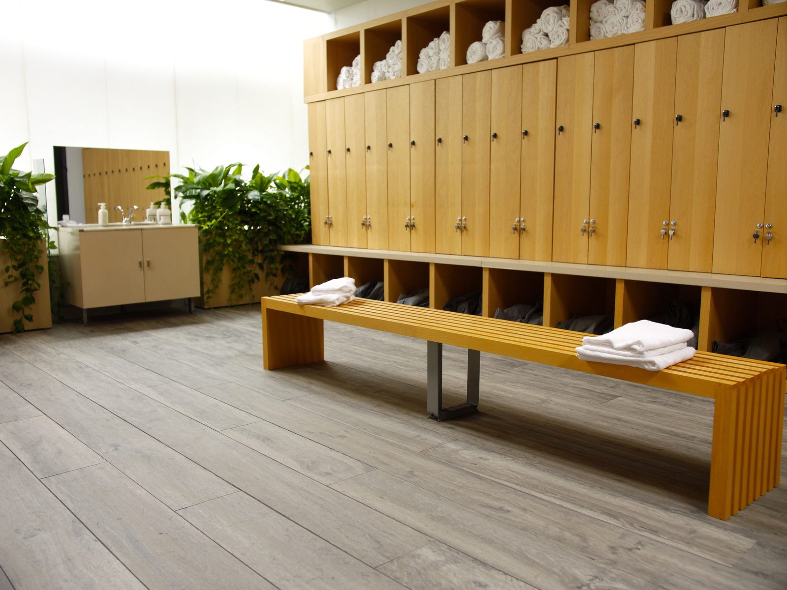 A clean gym locker room with oak lockers and towels