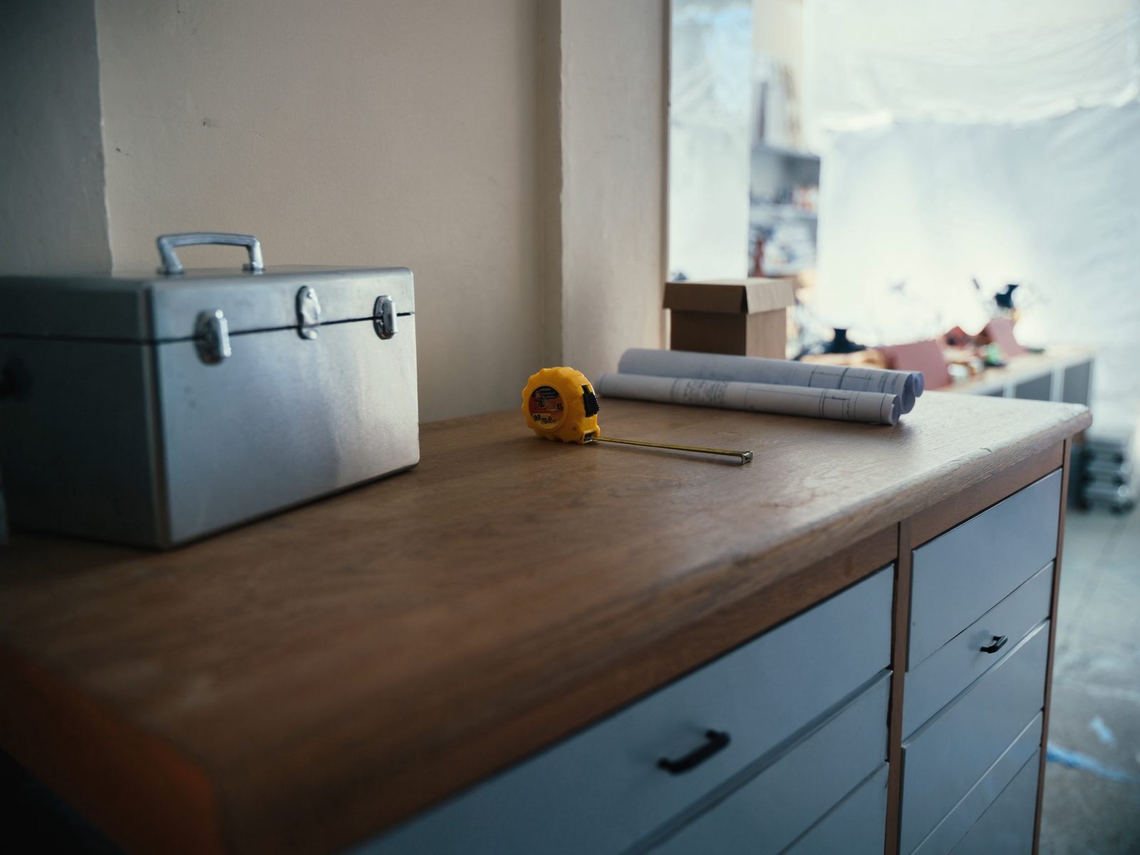 A toolbox, tape measure and blueprints on a workbench