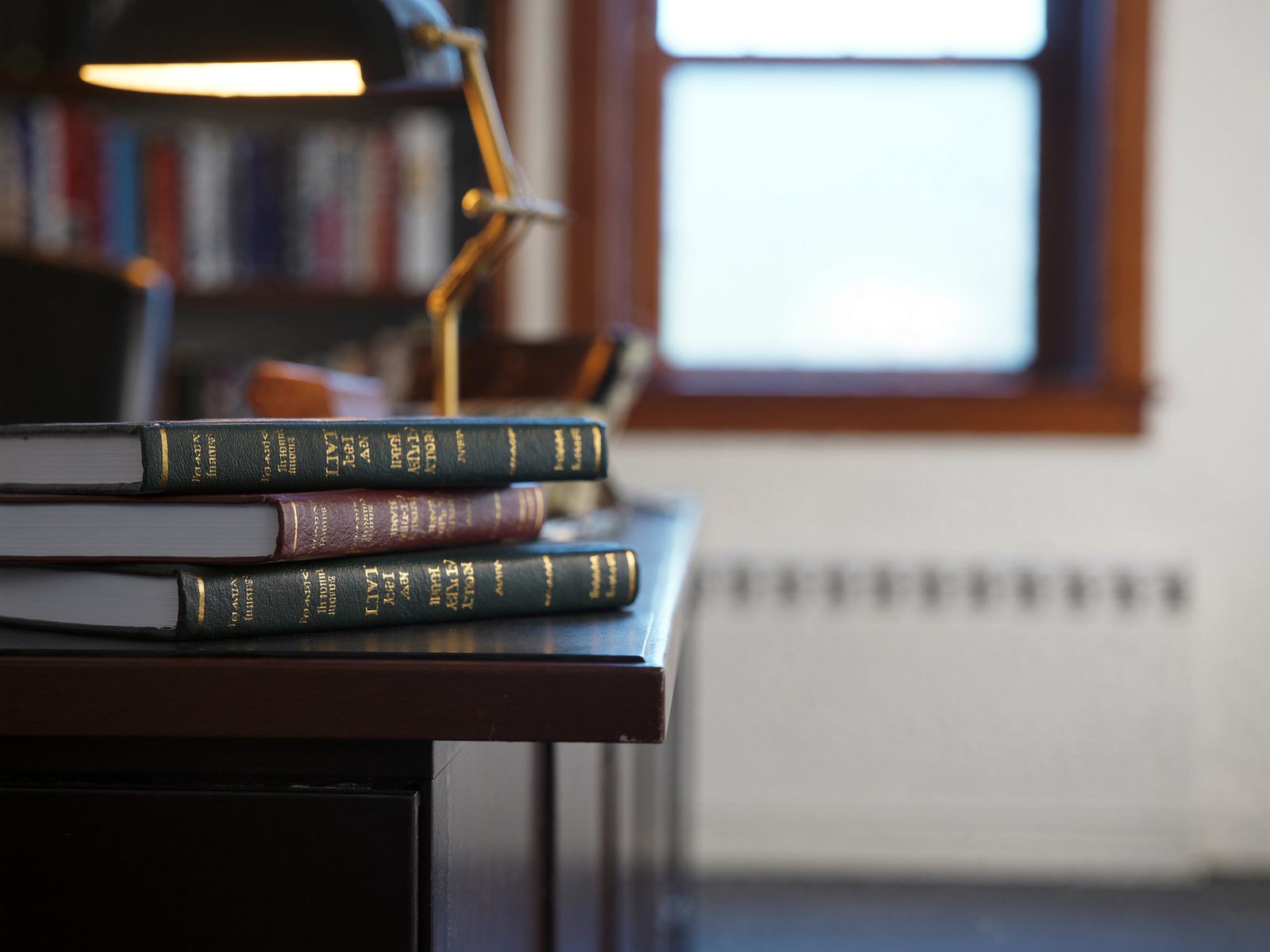 A stack of leather-bound law books beside a desk lamp