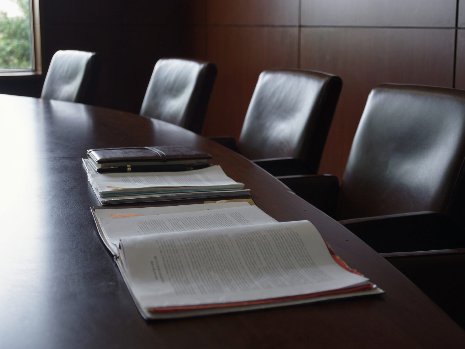Document folders and a pen on a conference table