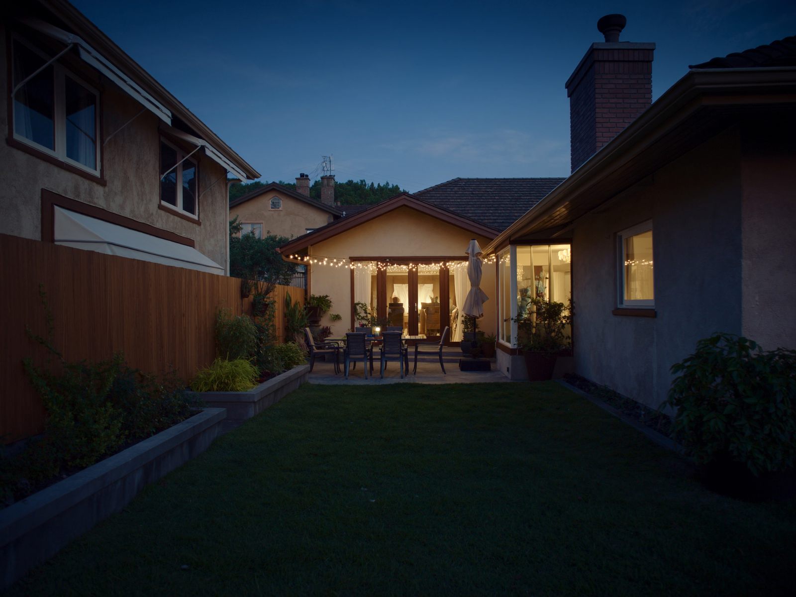 A backyard patio with string lights at dusk