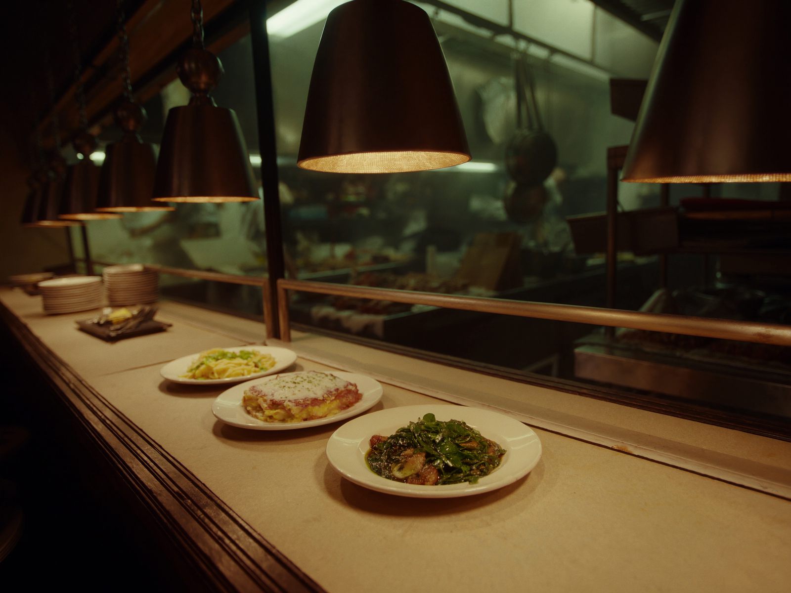 Plated dishes under heat lamps at a kitchen pass